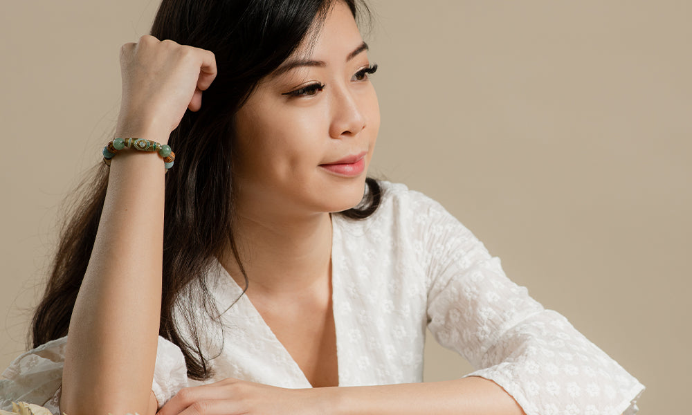 A woman sitting at a table wearing a Pixiu bracelet.